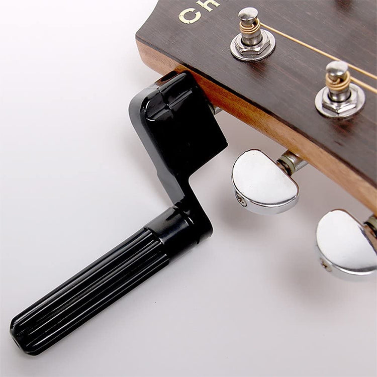 Guitar string winder tool with black handle near guitar tuning pegs