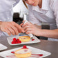 Pastry chef piping with teal silicone bag and stainless steel nozzle onto dessert