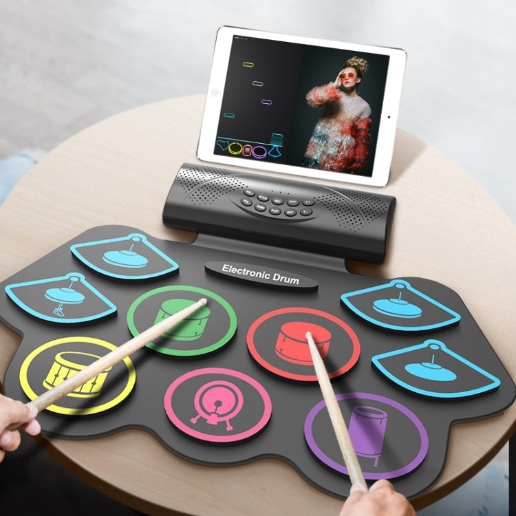 Portable electronic drum set with tablet display and two drumsticks on tabletop
