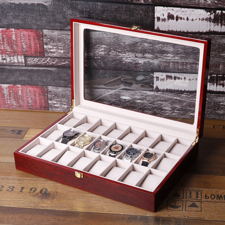 Red wooden watch box open with clear window lid and multiple watch slots on liner
