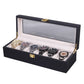 Black wooden watch box open with clear window lid and multiple watches in slots