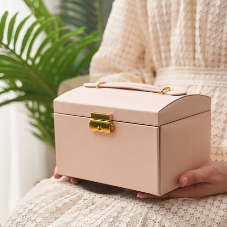 Nude pink jewelry storage box closed with gold-tone lock clasp, held by hand