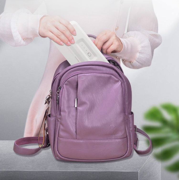 White UV handheld phone sterilizer held near purple mini backpack