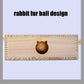 Wooden cat puzzle board with a dark plush ball in the tunnel opening.