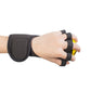 Hand wearing black grip device with thumb opening around yellow strengthening ball