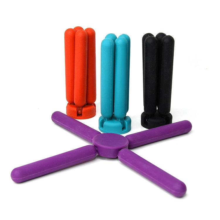 Multicolor cross-shaped folding silicone pot mat with purple, red, blue, and black arms.