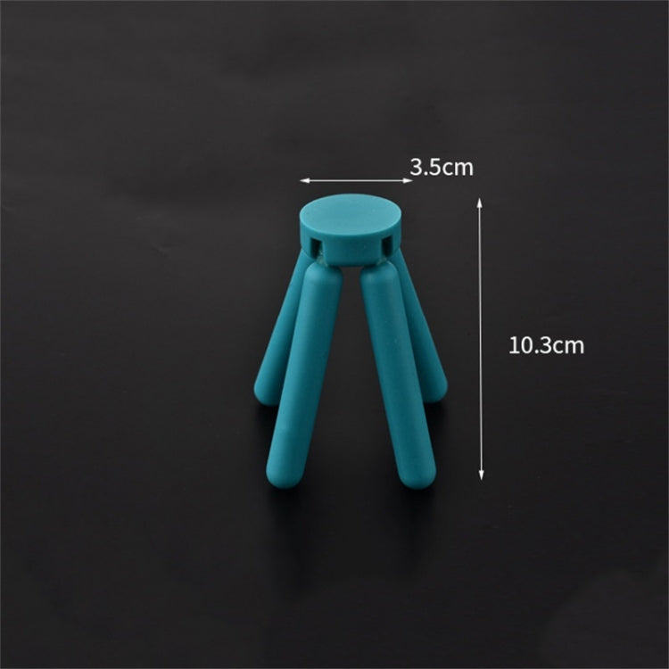 Teal cross-shaped folding silicone pot mat with three short legs, compact design.