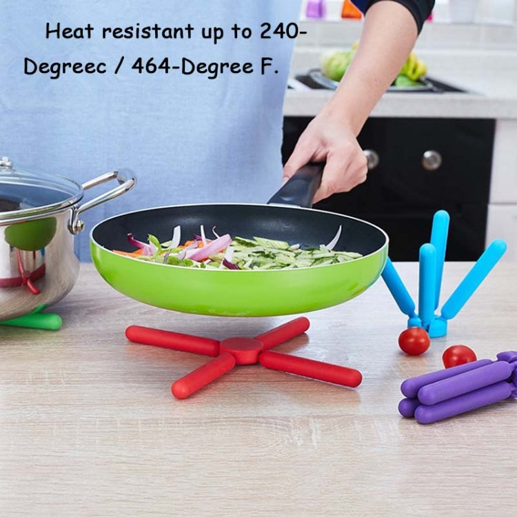Cross-shaped folding silicone pot mat set in blue and red with a purple piece beside cookware.