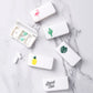Set of white portable medicine boxes with flamingo, cactus, leaf, pineapple, and “Stand Tall” lids
