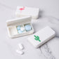 White 3-compartment medicine box with lid open and small pills inside