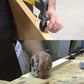 Hand using hinge groove chisel tool to cut a mortise in a wooden board