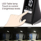 Black LED desk lamp with digital display and touch control; hand pointing at panel