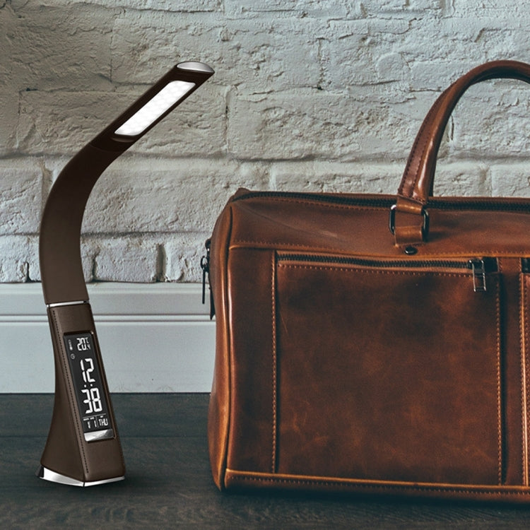 Black LED desk lamp with arched arm and glowing rectangular light panel on desk