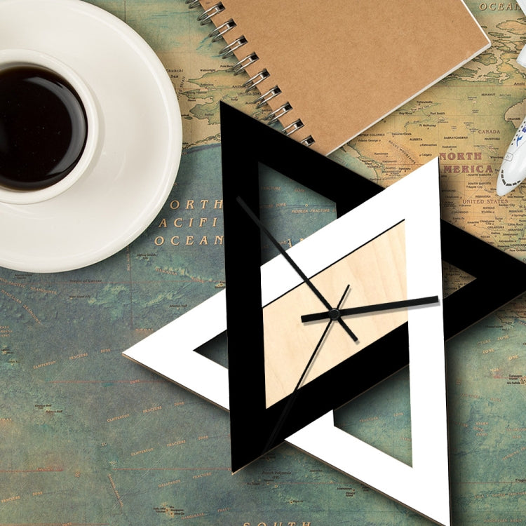 Geometric wall clock with star-shaped black and white frame and light wood dial, black hands