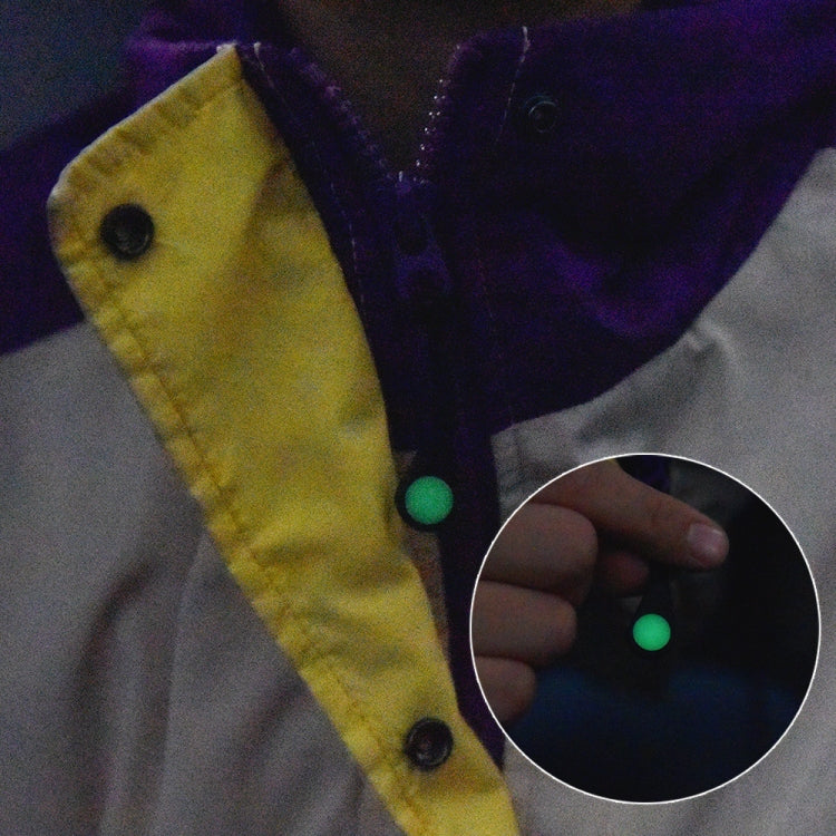 Luminous zipper pull on a jacket, hand holding a light green oval tip