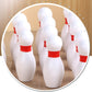 Close-up of red-and-white bowling pins inside wooden desktop base