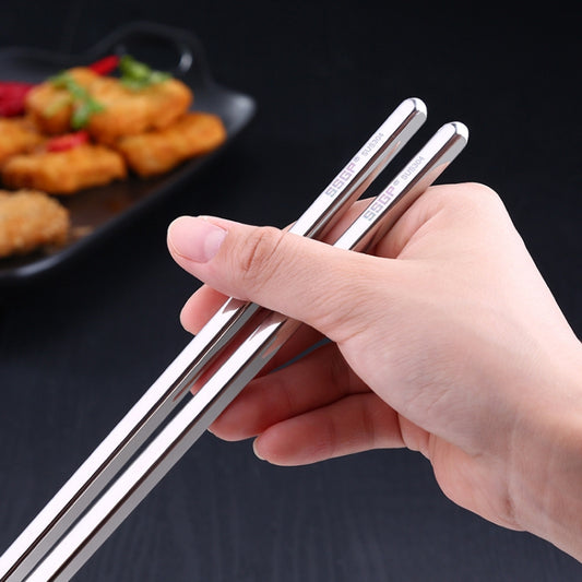 Hand holding stainless steel chopsticks with non-slip ridged section