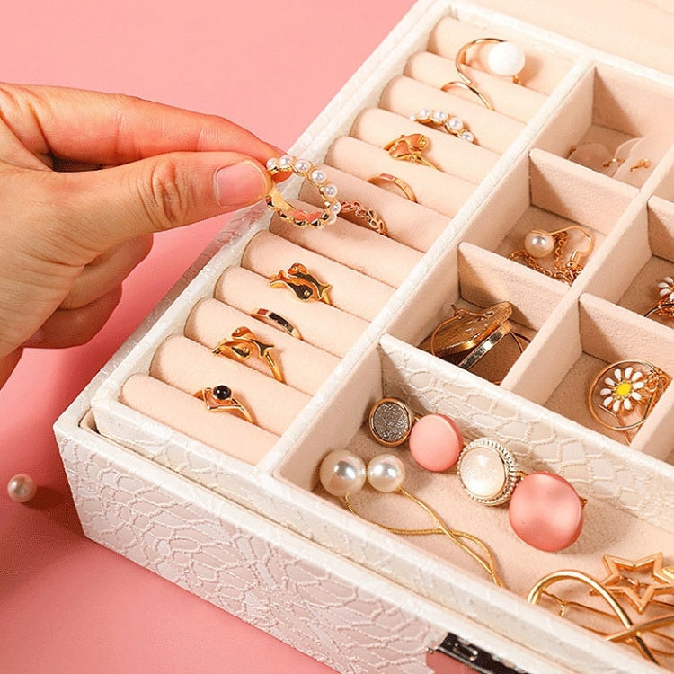 White jewelry box open with ring compartments, hand placing jewelry inside