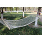 White cotton rope mesh hammock suspended between supports with spreader bar