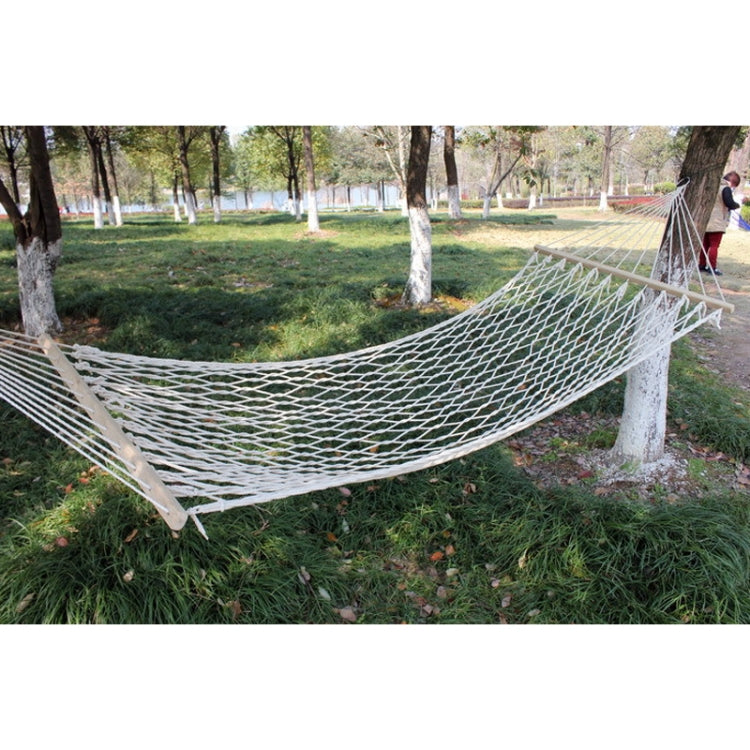 White cotton rope mesh hammock suspended between supports with spreader bar