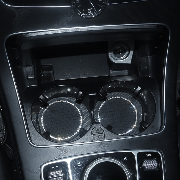 Two black honeycomb car cup coasters with rhinestone borders installed in cup holders.