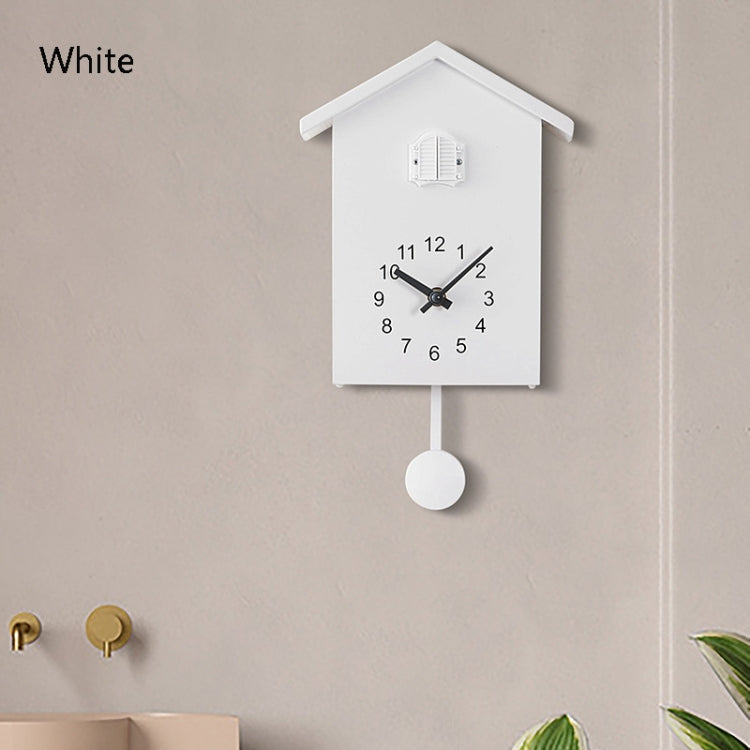 White cuckoo wall clock with round pendulum weight and bird housing on top