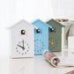 Set of white, blue, and green cuckoo wall clocks with pendulum weights and bird compartments