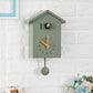 Green cuckoo wall clock with orange hands, pendulum weight, and bird speaker compartment