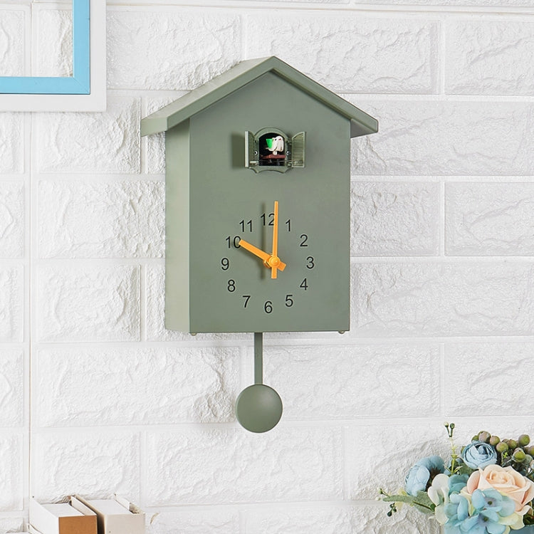 Green cuckoo wall clock with orange hands, pendulum weight, and bird speaker compartment