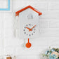 White cuckoo wall clock with orange hands, orange top, pendulum weight, and bird compartment