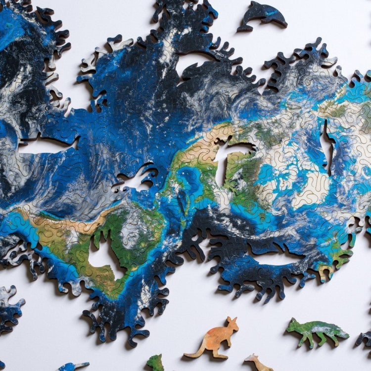 Wooden jigsaw puzzle with blue ocean pieces, green land, and animal cutout pieces