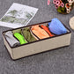 Beige drawer organizer with brown frame, open grid compartments holding folded clothes