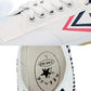 Close-up of white canvas upper and lace with blue and red stripe branding patch.