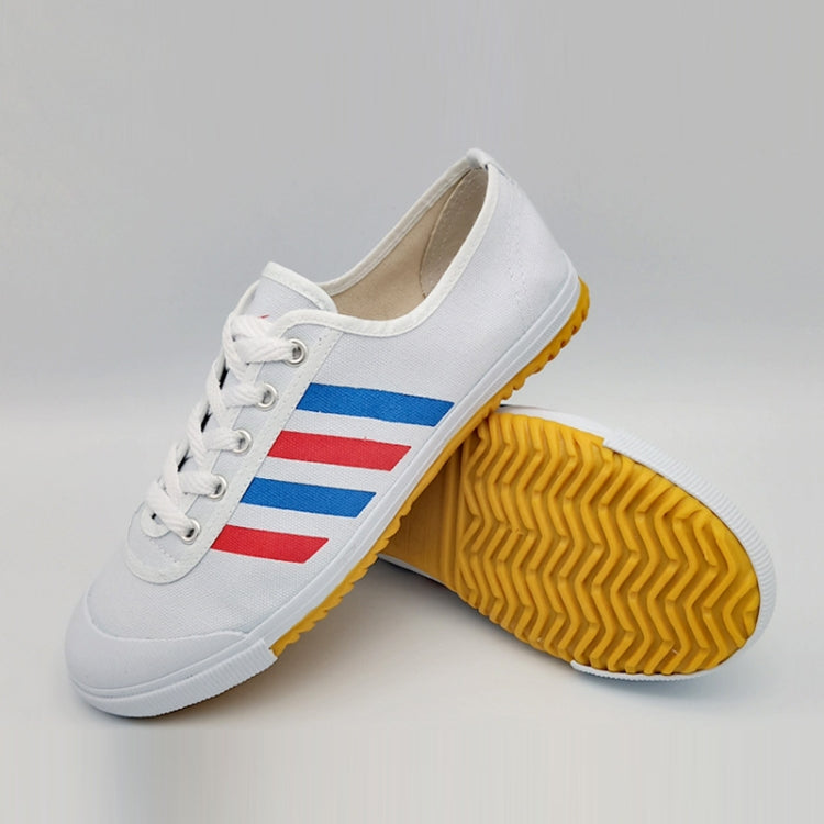 White canvas athletic shoe with lace-up front, blue/red stripe side, gum grip sole