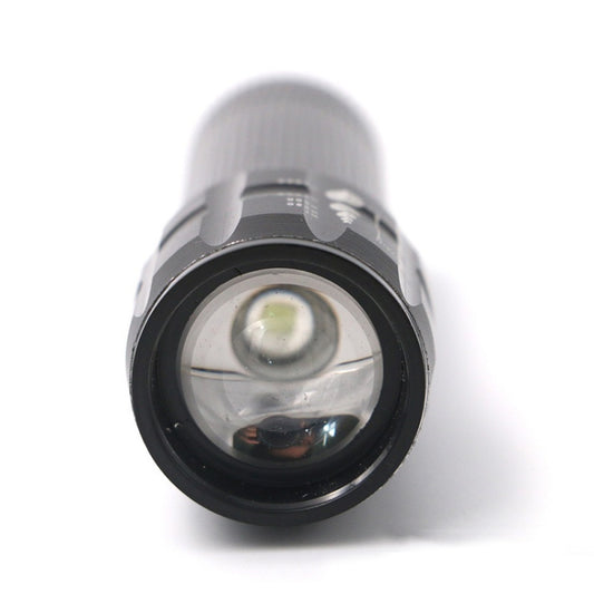 Mini LED flashlight head-on view with glass lens and surrounding black bezel.