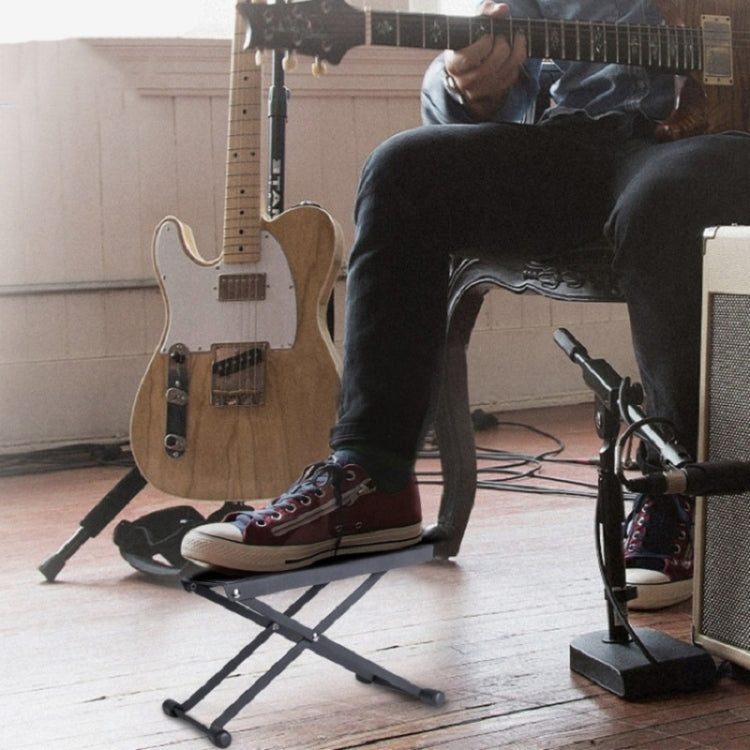 Musician using a black folding foot pad for guitar pedals on the floor
