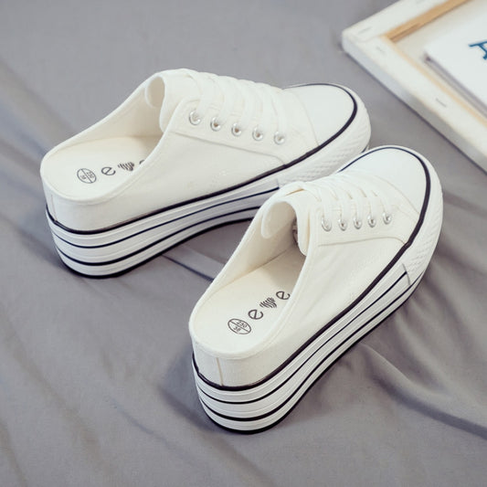 White canvas platform mule sneakers with lace-up front and thick striped sole.