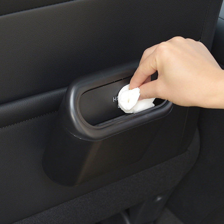 Black car trash can side slot as a tissue is inserted into the bin