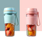 Portable mini juicer cups in blue and pink, both filled with fruit pieces