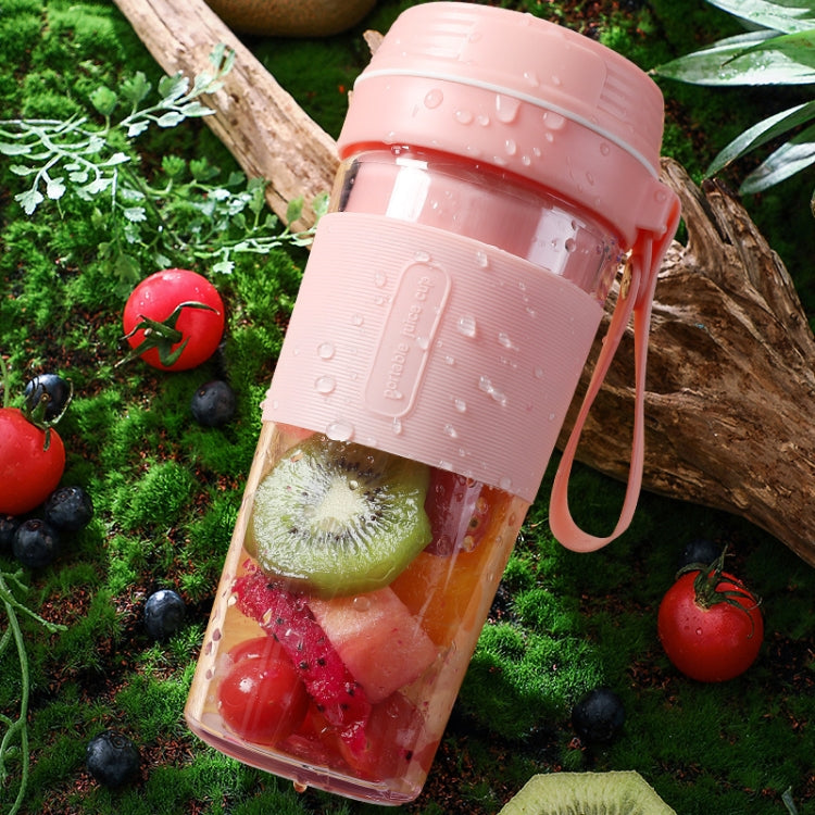 Pink portable mini juicer cup with fruit pieces and water droplets on the exterior