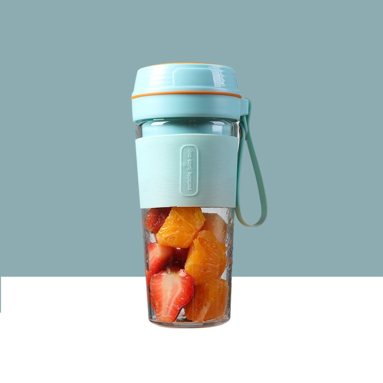 Portable mini juicer cup in light blue with fruit pieces inside and carrying loop