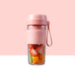 Pink portable mini juicer cup with fruit pieces inside and lid with carry handle