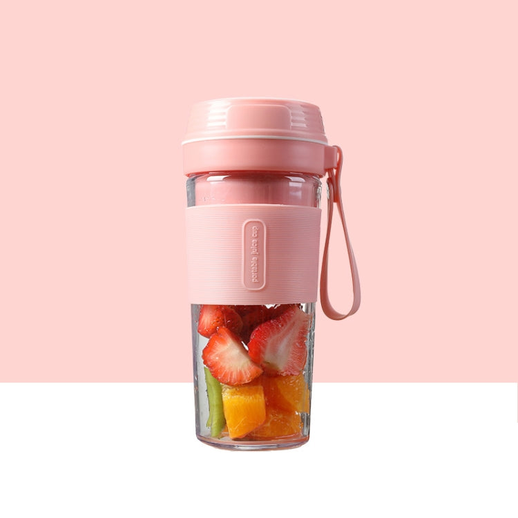Pink portable mini juicer cup with fruit pieces inside and lid with carry handle