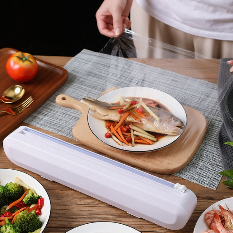 Cling film cutter box dispensing plastic wrap over a cutting board