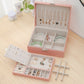 Pink jewelry box open with necklace rods, earring slots, and separate storage compartments