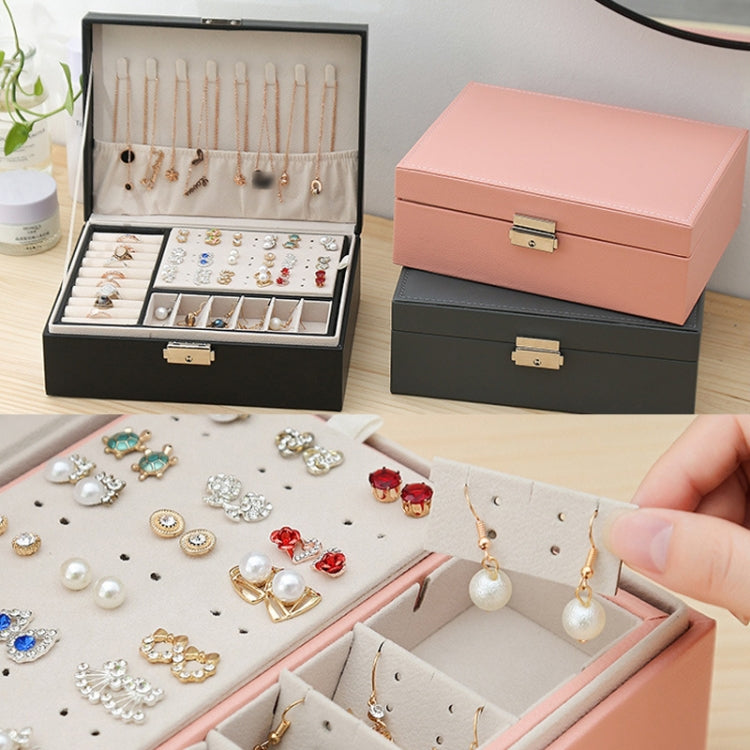 Black and pink jewelry boxes open with compartments and earrings on the trays