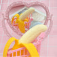 Peeling banana vent toy with cream banana segments and yellow peel by a pink basket