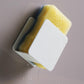White wall-mounted sponge rack with yellow sponge and water droplets