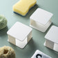 White wall-mounted sponge racks with yellow, green, and gray cleaning sponges
