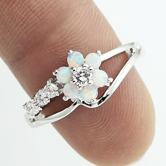 Opal flower ring detail on finger: round center stone with opal petal accents